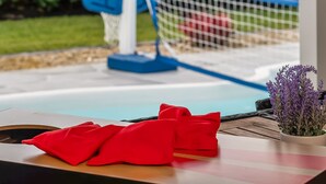 Un espace aménagé au bord de la piscine, avec une terrasse en bois, une serviette rouge et une chaise bleue.