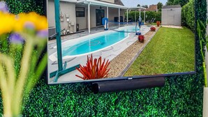 Un téléviseur à écran plat fixé au mur, avec un décor de gazon artificiel vert en arrière-plan.