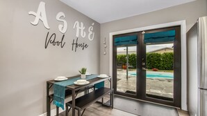 Un coin repas avec une table dressée pour deux personnes, un banc et un mur orné d’une citation inspirante.