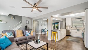 Un salon moderne avec un canapé gris, une table basse et un ventilateur de plafond.