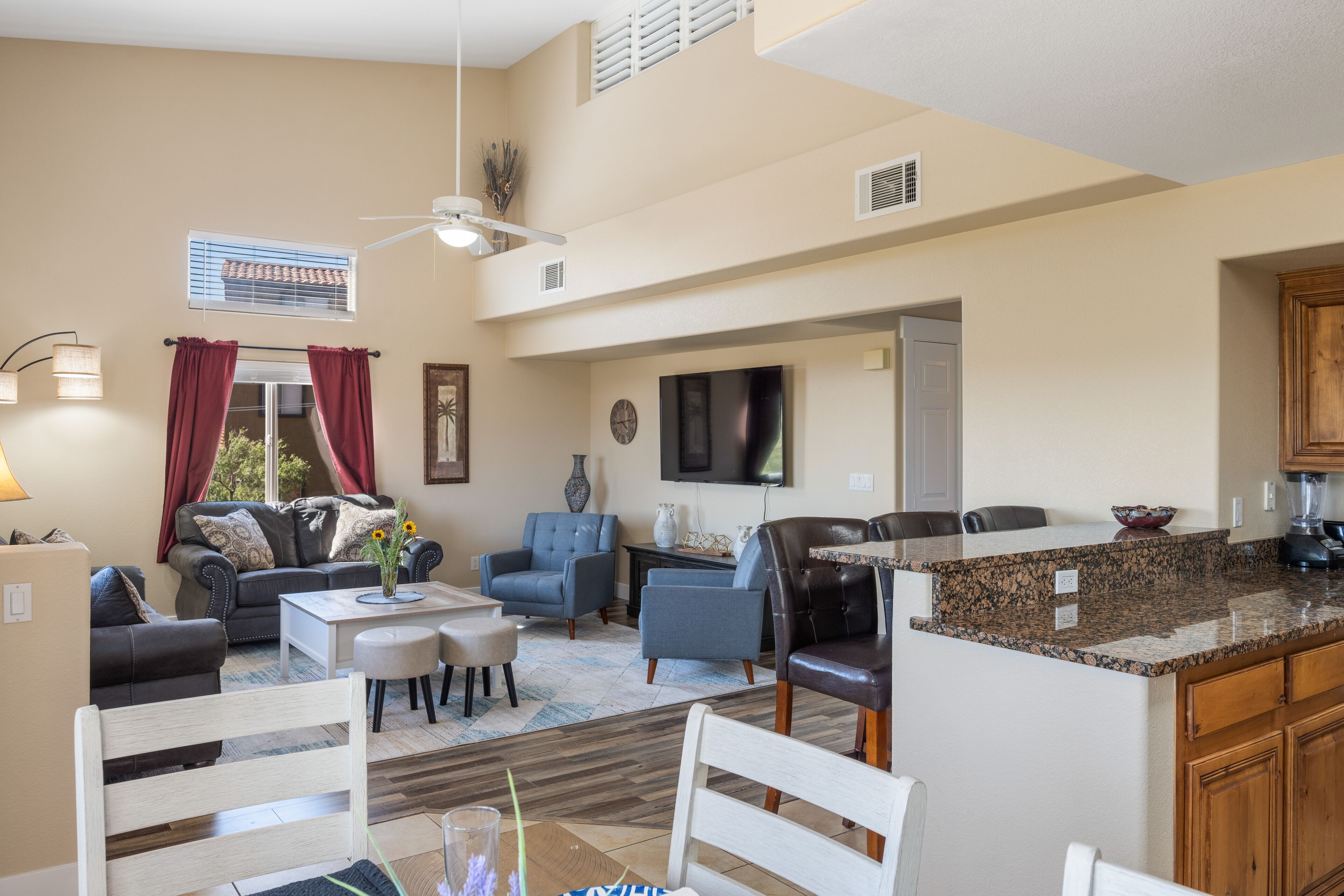 A spacious living area with a dining table, sofas, and a kitchen with granite countertops.