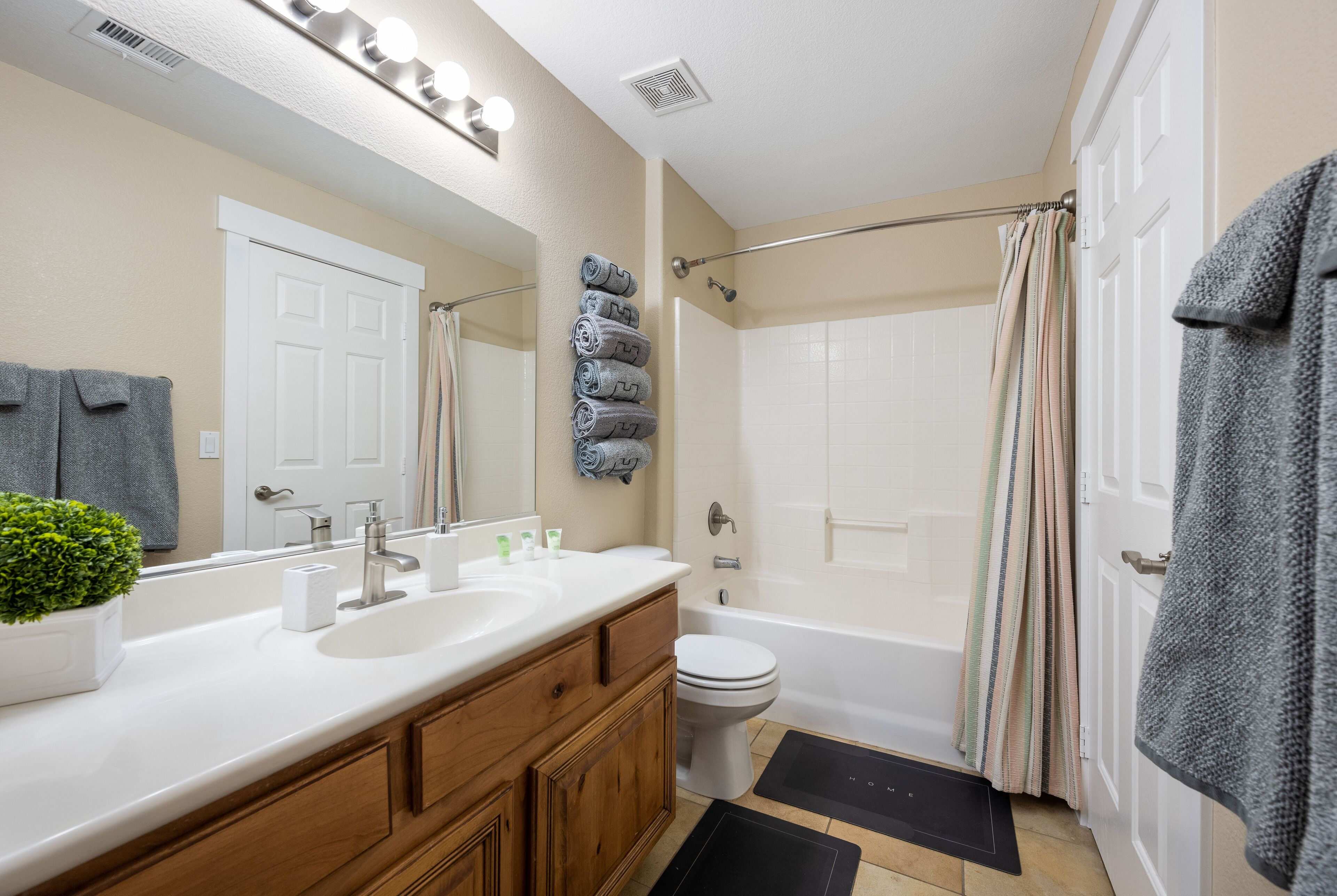 A bathroom with a sink, mirror, and toilet. There are towels and a shower curtain.