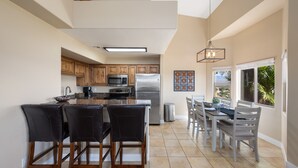 A spacious kitchen with a central island, wooden cabinets, and a dining area with chairs and a table. - The Oasis - Golf - Pool - Hot Tub - Condo with a View. (Mesquite)