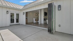 Una casa moderna con un amplio patio abierto, un comedor con mesa y sillas, y una puerta corrediza de vidrio que da a un espacio interior.