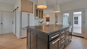 Una cocina moderna con una isla grande, armarios de madera e iluminación colgante.