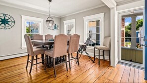A dining area with a wooden table and chairs, a hanging light fixture, and a view of the outside. - Beautiful Beach Cottage in Downtown Bristol (Bristol)