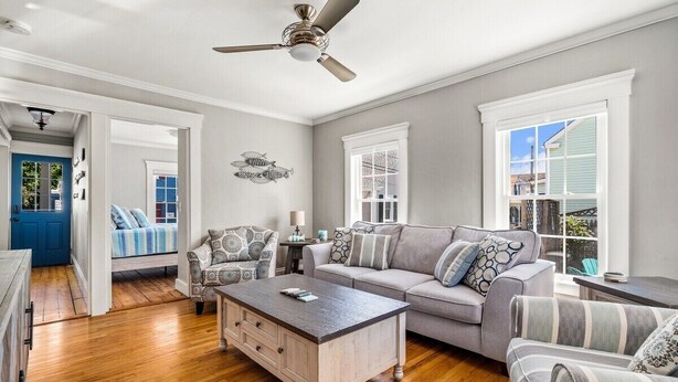A spacious living room with hardwood floors, a gray sofa, patterned armchairs, a coffee table, and a ceiling fan. - Beautiful Beach Cottage in Downtown Bristol (Bristol)