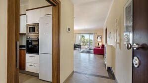 A modern kitchen with white cabinets, a built-in microwave, and a stainless steel refrigerator. - Modern Apartment with Free Wifi and communal swimming pool in O POMAR Cabanas (Cabanas de Tavira)