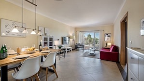 A modern kitchen with a dining area, a red sofa, and a TV. - Modern Apartment with Free Wifi and communal swimming pool in O POMAR Cabanas (Cabanas de Tavira)