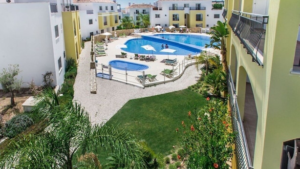 A courtyard with two swimming pools, lounge chairs, and a small garden area. - Modern Apartment with Free Wifi and communal swimming pool in O POMAR Cabanas (Cabanas de Tavira)
