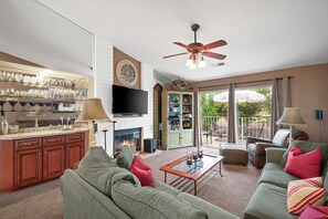 A spacious living room with a fireplace, a television, and a balcony with outdoor furniture.