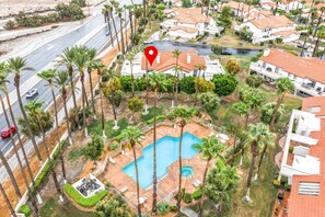 A residential area with a large swimming pool surrounded by palm trees and houses.