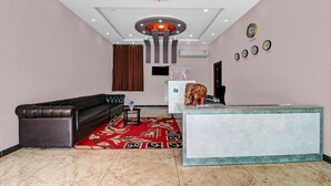 A hotel lobby with a leather sofa, a reception desk, a patterned carpet, and a chandelier. - Itsy Hotels Kattari Komforts, Chikmagalur (Chikkamagaluru)