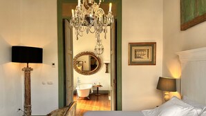 Un dormitorio con una cama grande, una araña, un espejo y un cuadro en la pared.