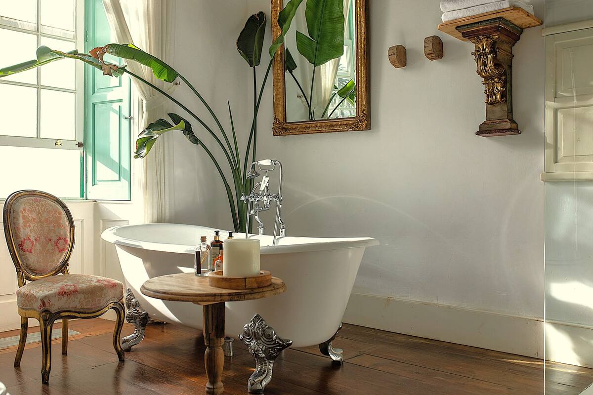 Ein Badezimmer mit einer freistehenden Badewanne, einem Spiegel und einem Sessel.