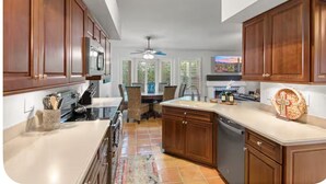 Una cocina con armarios de madera, lavavajillas y un comedor con sillas y mesa.