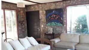 A living room with a stone wall, two sofas, a coffee table, and a painting. - Chalet frente al  mar  Sta Monica  J Ignacio (Jose Ignacio Sta Monica)
