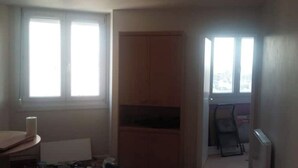 A room with a large window, a wooden cabinet, and a radiator. - MERIDIEN-STUDIO 3* ALL-COMFORT (Dunkerque)