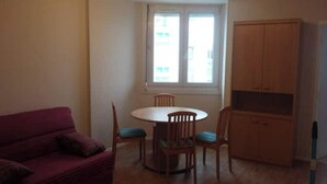 A room with a dining table and chairs, a red sofa, and a wooden cabinet. - MERIDIEN-STUDIO 3* ALL-COMFORT (Dunkerque)