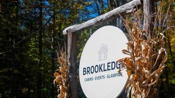 Señal para las cabañas, eventos y glamping de Brookledge, con un marco de madera rústica y un letrero circular blanco.