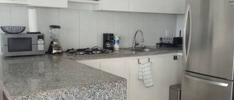Eine moderne Küche mit weißen Schränken, Granit Arbeitsplatten, Edelstahlgeräten und Pendelleuchten.