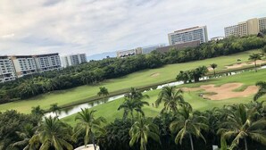 A view of a golf course with a swimming pool, palm trees, and high-rise buildings in the background. - CONDO FLAMINGO  BY TRVL2HM (Nuevo Nayarit)