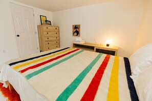 Ein Schlafzimmer mit Bett, Kommode, Nachttisch und einer Tür.