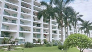 A multi-story hotel with balconies, surrounded by palm trees and a well-maintained lawn. - CONDO ARIAN  BY TRVL2HM (Bucerías)