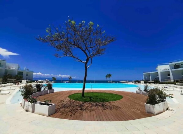 Un espace piscine agrémenté d’un arbre au centre, entouré d’une terrasse circulaire en briques.