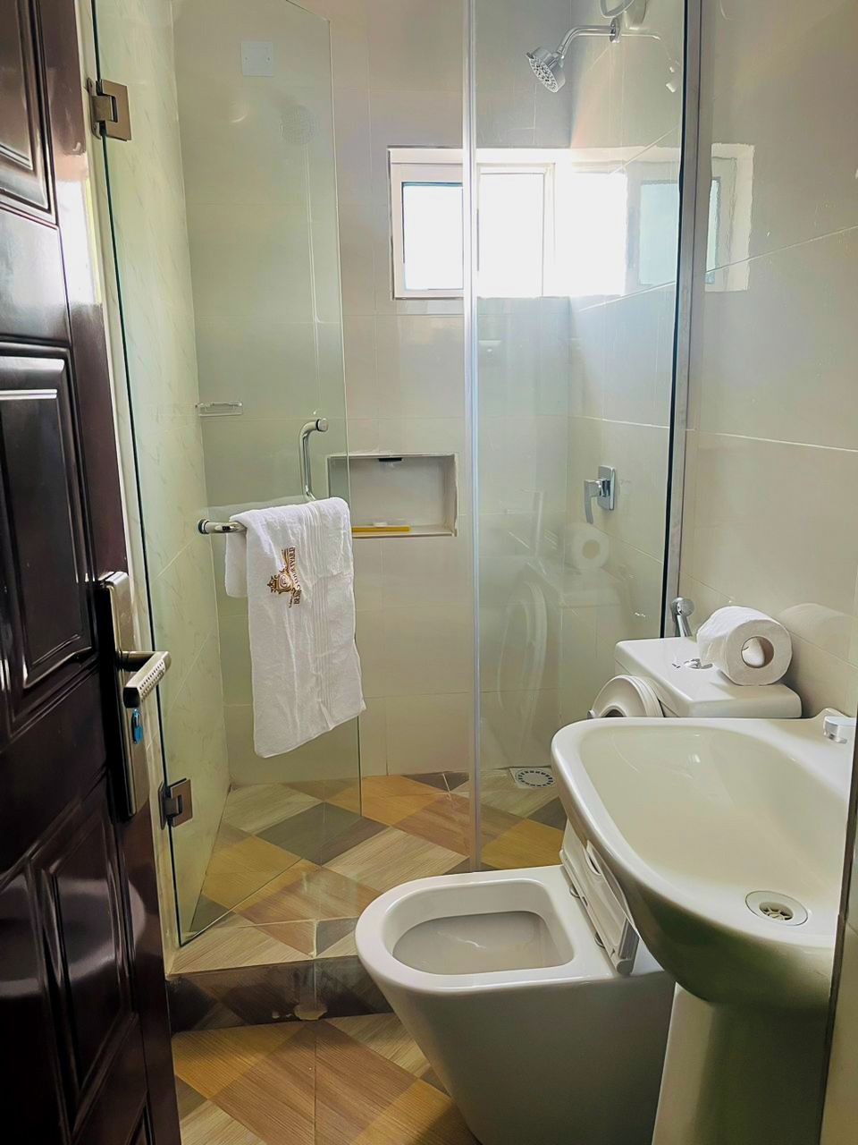 A bathroom with a glass-enclosed shower, a toilet, and a sink.