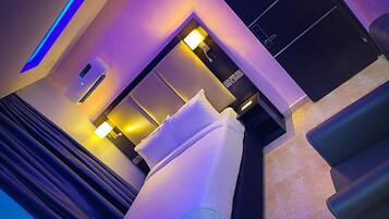 A modern hotel room with a bed, bedside tables, and ambient lighting.