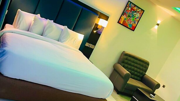 Quarto de hotel moderno com uma cama grande, um sofá e uma mesinha.