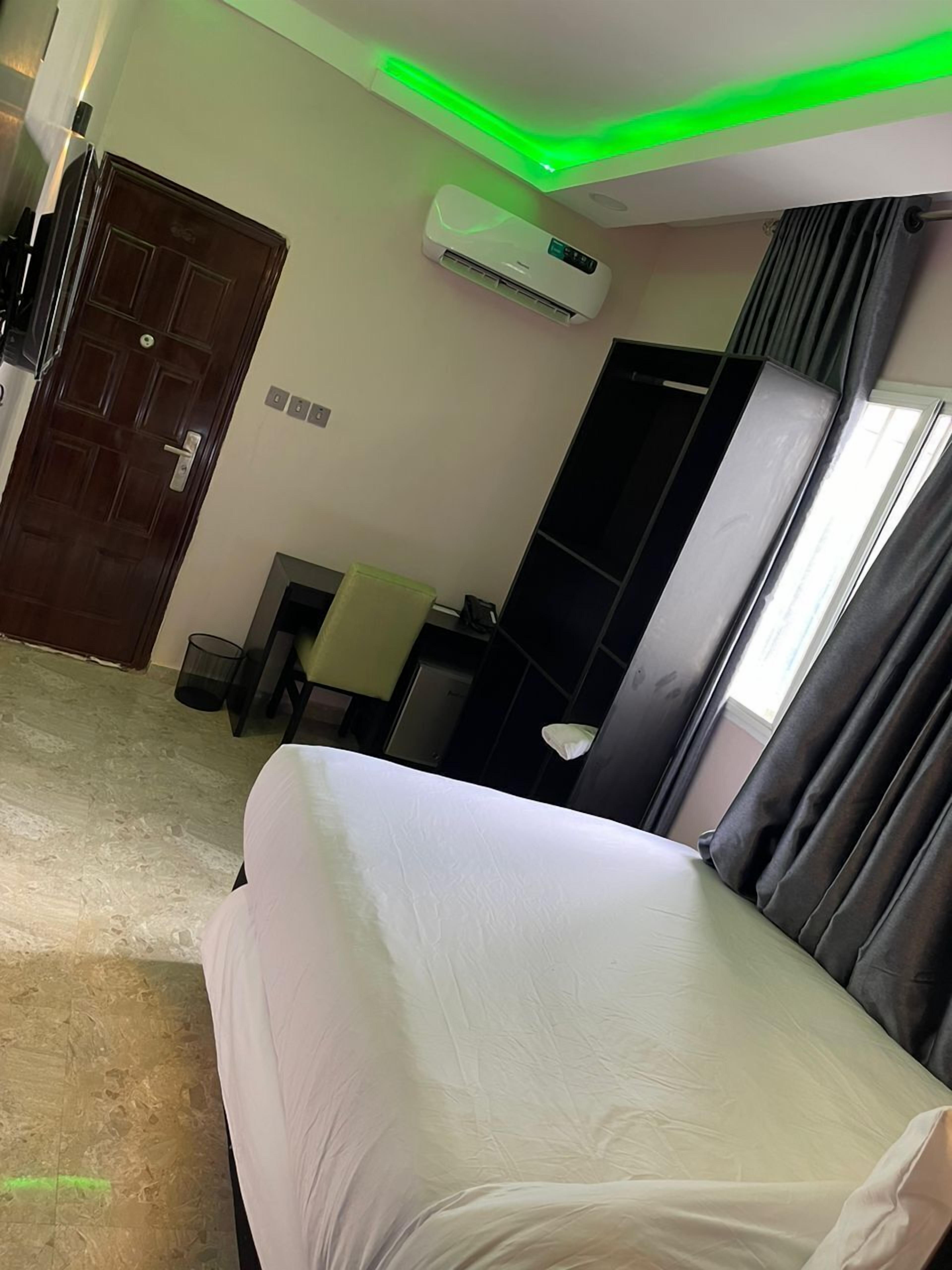 Une chambre d’hôtel équipée d’un lit, d’un appareil de climatisation, d’un bureau, d’une chaise et d’une fenêtre avec des rideaux.