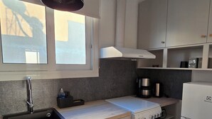 A compact kitchen with a sink, stove, and white cabinets.