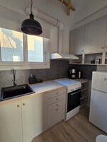 Cocina compacta con lavamanos, estufa y armarios blancos.