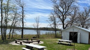 Een picknickplaats aan het meer, met houten banken en een klein tuinhuis.