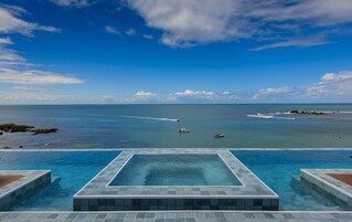 Una piscina al aire libre, sombrillas, sillones reclinables de piscina