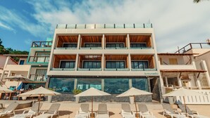 A two-story building with a beachside location, featuring multiple balconies, outdoor seating, and a visible restaurant sign. - Pousada Antonella (Cairu)