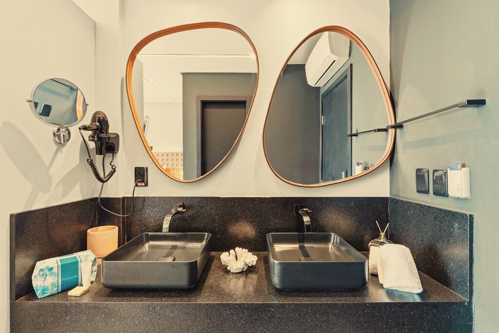 Casa de banho com duas pias, um secador de cabelo, um espelho e um porta-toalhas.