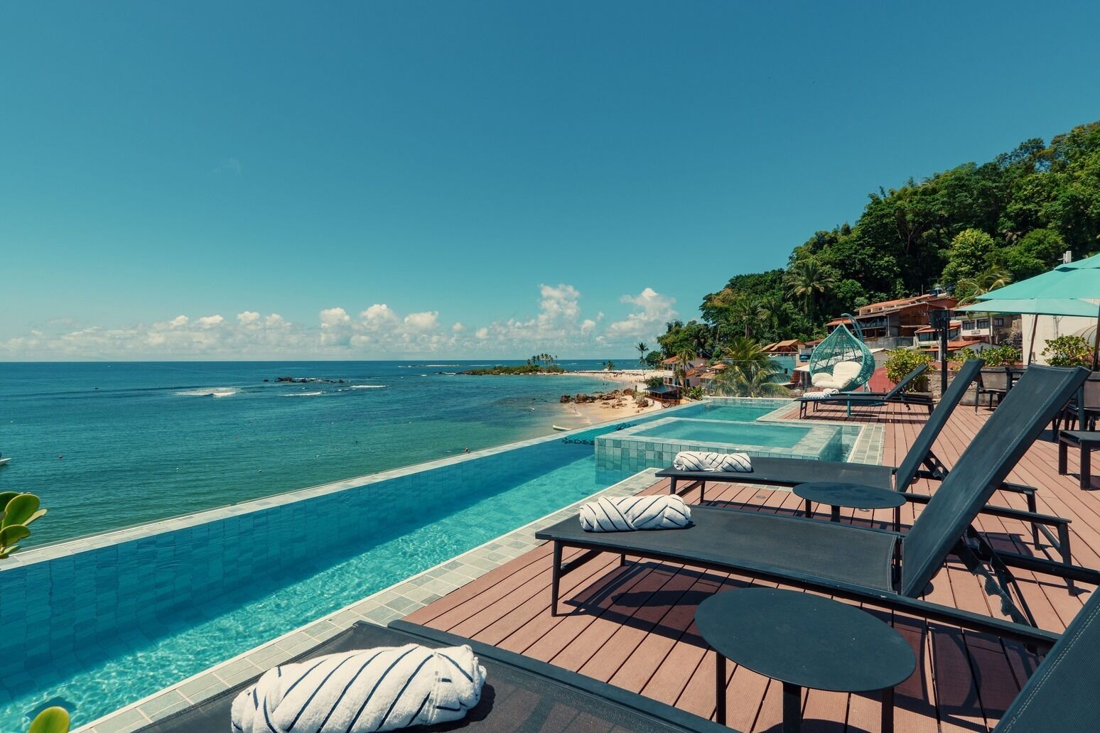 Un espace aménagé au bord de la piscine, avec des chaises longues et une vue sur l’océan.