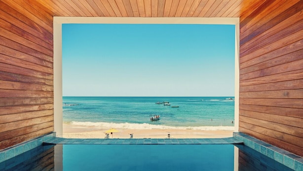 A pool with a view of the beach and ocean. - Pousada Antonella (Cairu)