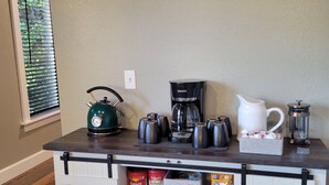 A kitchen counter with coffee-making equipment, a coffee bar sign, and storage for coffee beans and tea. - Cozy, remodeled townhome retreat in downtown Historic Wallace! (Wallace)