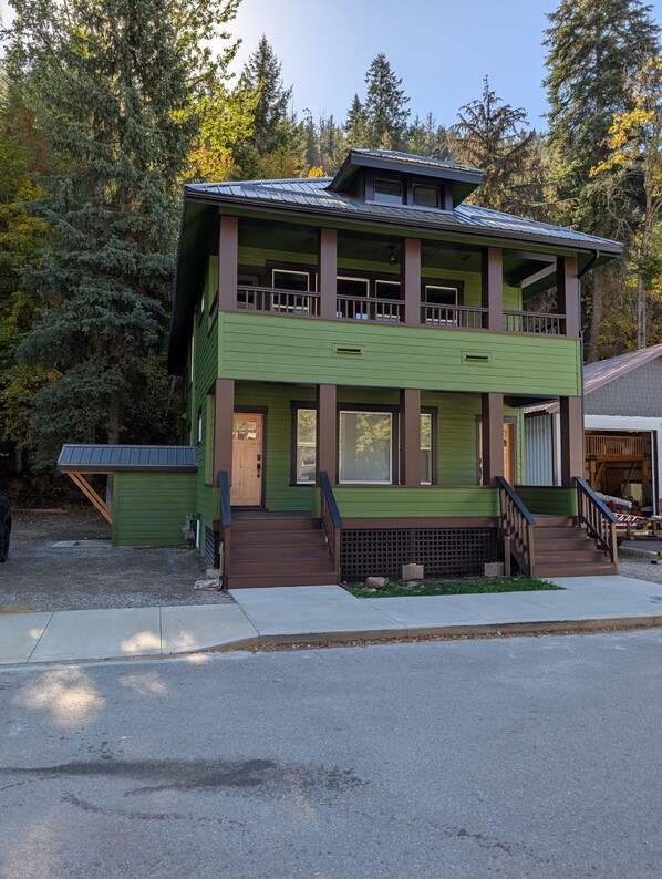 A two-story building with a green exterior and a balcony on the upper floor. - Cozy, remodeled townhome retreat in downtown Historic Wallace! (Wallace)