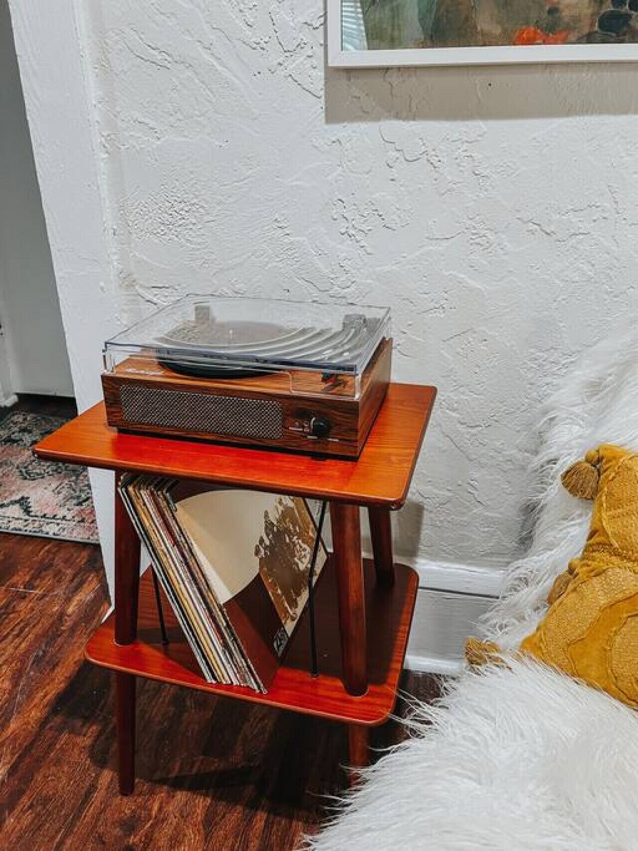 Una mesita de madera con un tocadiscos de vinilo y una pila de discos.