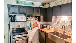 Une cuisine de taille réduite, avec des meubles de couleur sombre, un four à micro-ondes, un grille-pain et un évier.
