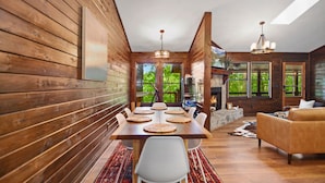 Un intérieur en bois comprenant une table à manger, des chaises, un canapé et une cheminée.