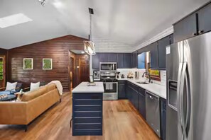 A modern kitchen with a central island, built-in appliances, and a wooden accent wall. - Luxury Cabin w/ views•Toccoa•<br> HotTub•Firept•Pets (Blue Ridge)