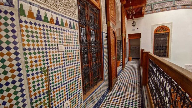 A corridor with intricate tile work and wooden railings. - Suite Avec 4lits Dans un Riad Luxueuse a fes (fes)