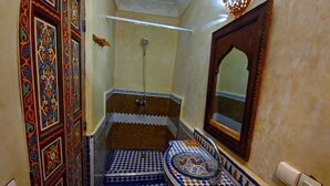 A bathroom with a checkered floor, a sink with a decorative tile, and a shower area. - Suite Avec 4lits Dans un Riad Luxueuse a fes (fes)