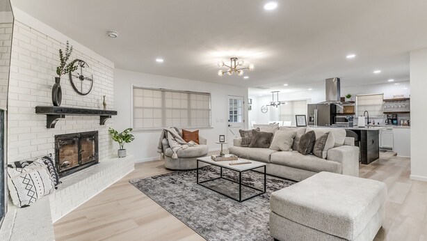 A modern living room with a fireplace, a sofa set, and a kitchen area in the background. - Chic OKC Retreat Near Lake Hefner -Family Friendly (Oklahoma City)
